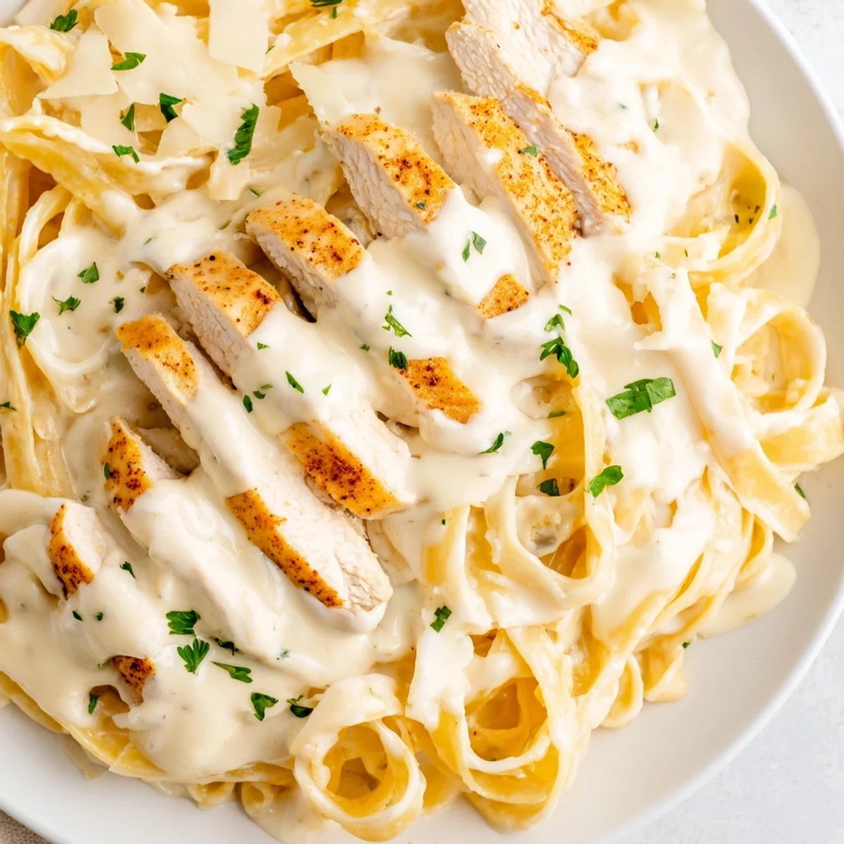 Steaming plates of Cajun Chicken Alfredo feature golden seared chicken strips draped over creamy fettuccine, garnished with vibrant parsley and freshly grated Parmesan.