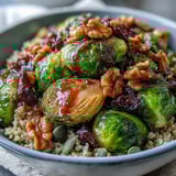 A close-up of caramelized Brussels sprouts and onions in a Roasted Brussels Sprouts Bowl, topped with walnuts and cranberries.