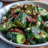 A vibrant smashed cucumber salad drizzled with spicy garlic chili oil and sesame seeds.