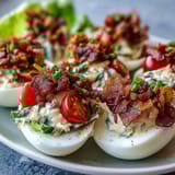 Deviled eggs filled with creamy yolk mixture and topped with crispy bacon crumbles and fresh lettuce for a BLT twist.