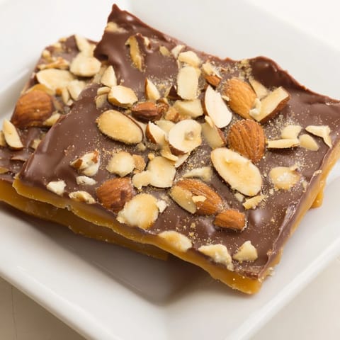 Melted milk chocolate blankets the perfect English toffee, sprinkled with crunchy almonds after baking.