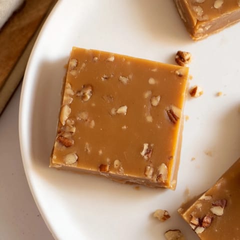 A close-up of creamy, smooth Penuche Fudge, ready to be sliced, offering a delicious caramel aroma.
