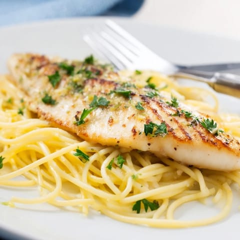 Steaming platter of Lemon Bass Pasta with tender sea bass fillets, vibrant herbs, and a light lemon-butter sauce perfect for weeknight dinners.