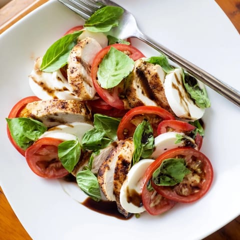 A vibrant platter of Chicken Caprese Salad with creamy mozzarella, juicy tomatoes, and fragrant basil leaves.  