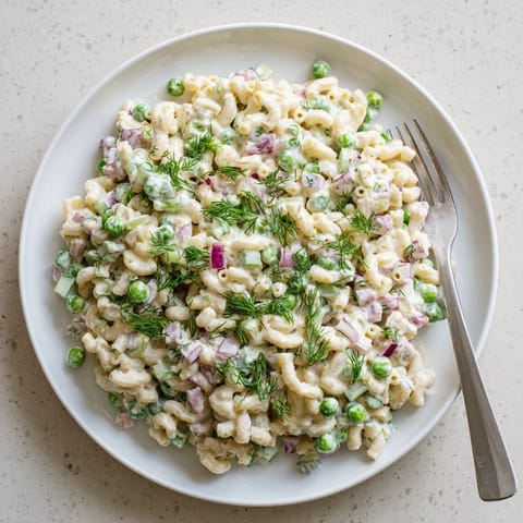 Creamy Dill Pickle Pasta Salad served chilled in a white bowl, garnished with fresh dill and red onion, perfect for potlucks.