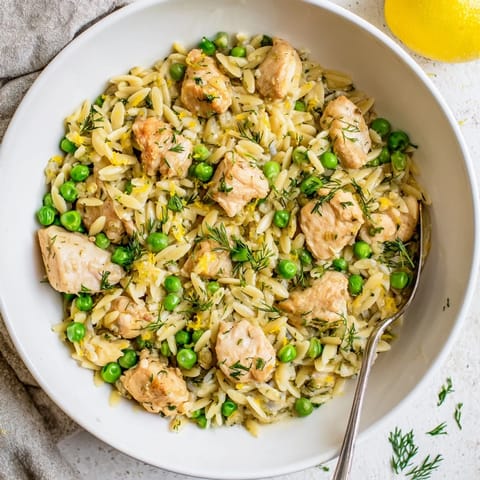 Golden-brown chicken thighs and tender orzo mingle with sweet peas and fresh dill in a vibrant one-pan skillet ready for dinner.