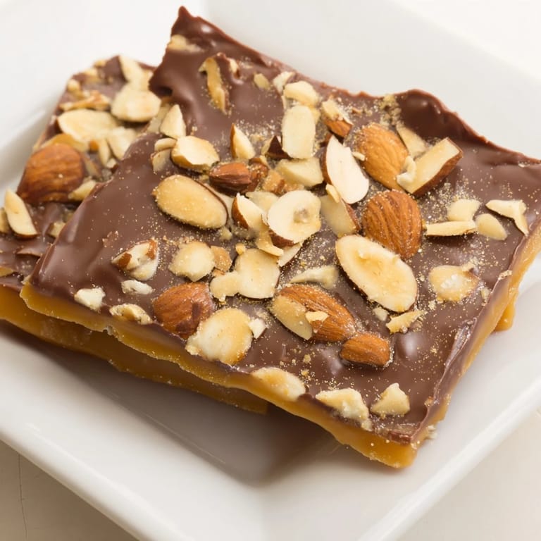 Melted milk chocolate blankets the perfect English toffee, sprinkled with crunchy almonds after baking.