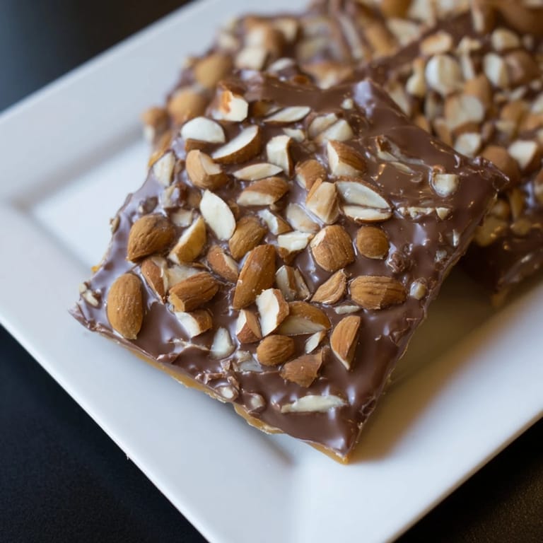 Enjoy the crispy, sweet perfection of this English toffee, featuring a rich chocolate and nut topping.
