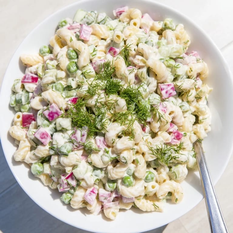 Close-up of Creamy Dill Pickle Pasta Salad featuring crunchy pickles and sweet peas tossed in a rich, tangy dressing.