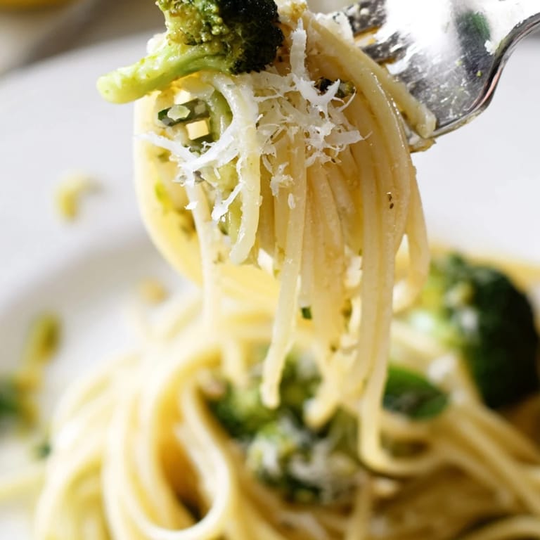 A close-up of steaming One-Pot Lemon Broccoli Pasta garnished with fresh basil and grated Parmesan, ready to serve.