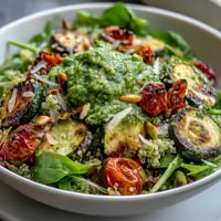 Freshly made Arugula Pesto Bowl with fluffy quinoa, roasted zucchini, and cherry tomatoes topped with shaved Parmesan.