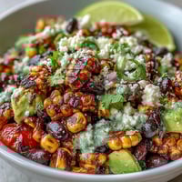 Grilled corn and black bean taco salad with fresh avocado and lime dressing, served in a large bowl.  